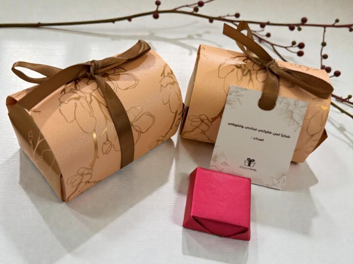 Two rose gold Belgian chocolate favor boxes with personalized tag and wrapped chocolate