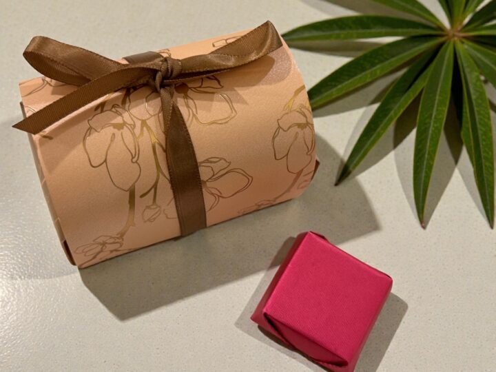 Rose gold Belgian chocolate favor box with brown ribbon and wrapped chocolate piece