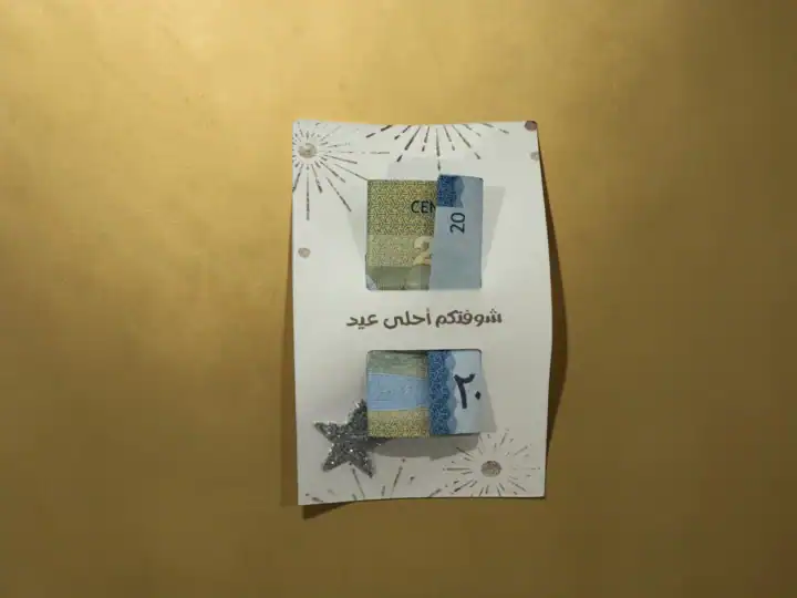 كرت العيدية — ٣ تصاميم مع فتحات لتعليق النقود 2 Close-up of Eidiyah money card with banknotes inserted and glitter star detail