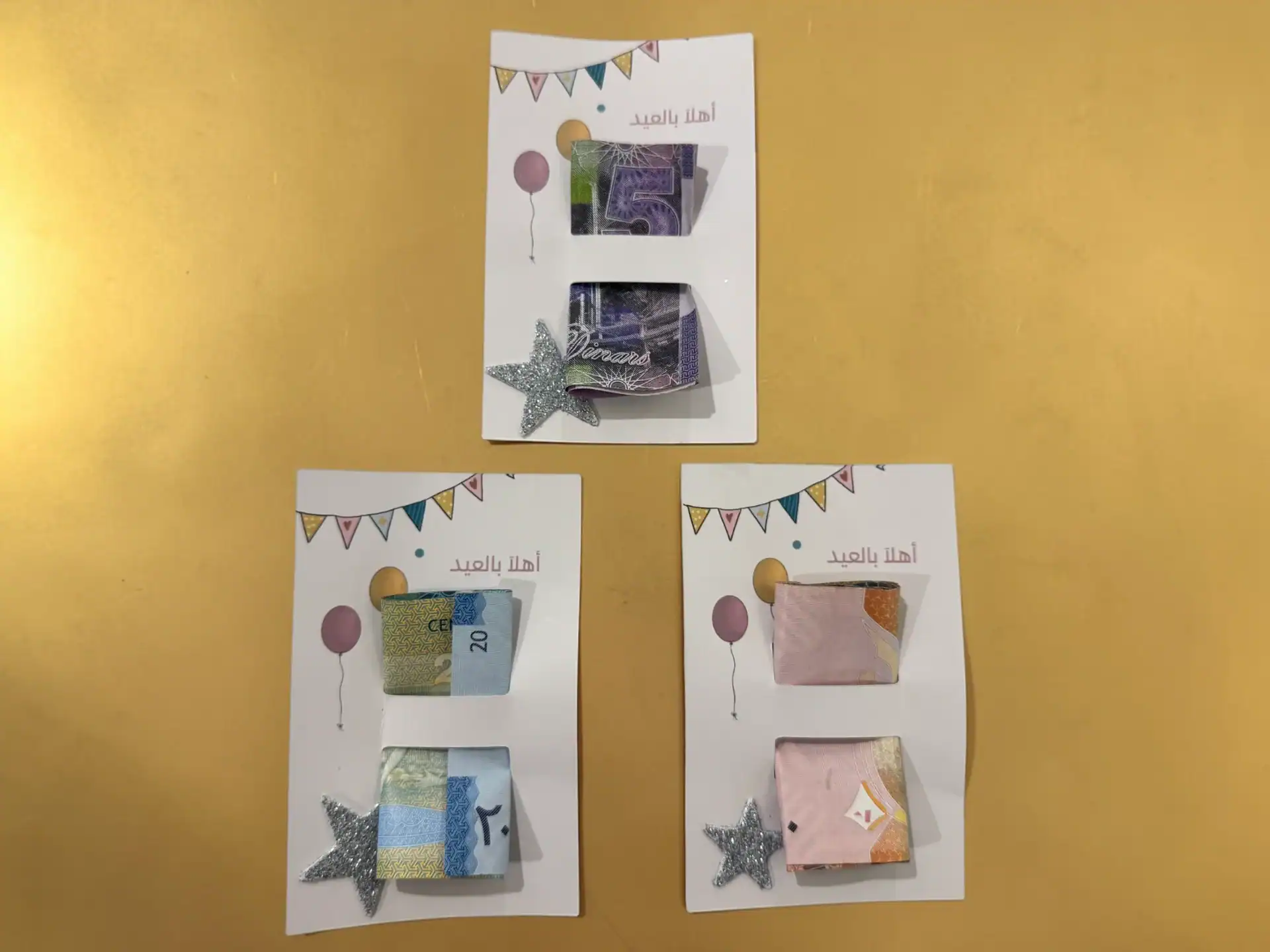 كرت العيدية — ٣ تصاميم مع فتحات لتعليق النقود 1 Set of party Eidiyah money cards with bunting and balloons, cash slots, and glitter star