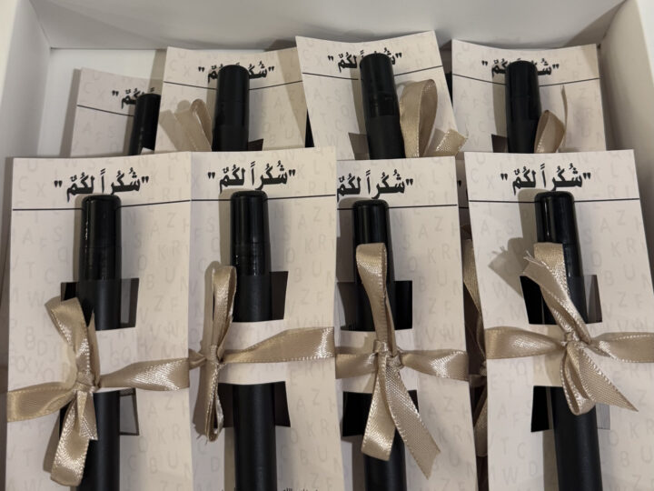 Bulk box of beige card perfume favors with off-white ribbons